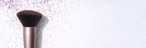 Banner. Festive holiday and Christmas makeup concept. Makeup brush over white holographic background with purple sparkles and glitter around. Template with copy space for text - Foto, Imagem