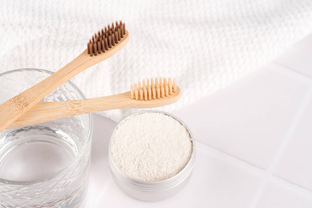 Closeup view of wooden toothbrushes with mineral toothpowder kaolin in alu container over white table background. Natural bath products, organic dentifrice - Fotó, kép