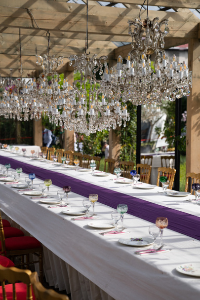 Copas y vasos de vidrio, platos blancos, cubiertos para la mesa festiva para la boda de lujo o fiesta de cumpleaños al aire libre. Luz solar. Enfoque suave. - Foto, imagen