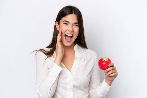 Mladá brazilská žena s jablkem izolované na bílém pozadí křičí s ústy široce otevřenými - Fotografie, Obrázek
