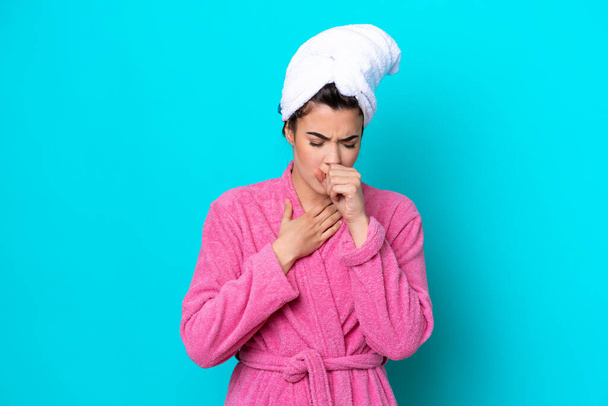 Young Brazilian woman with a bathrobe isolated on blue background is suffering with cough and feeling bad - Foto, Imagen