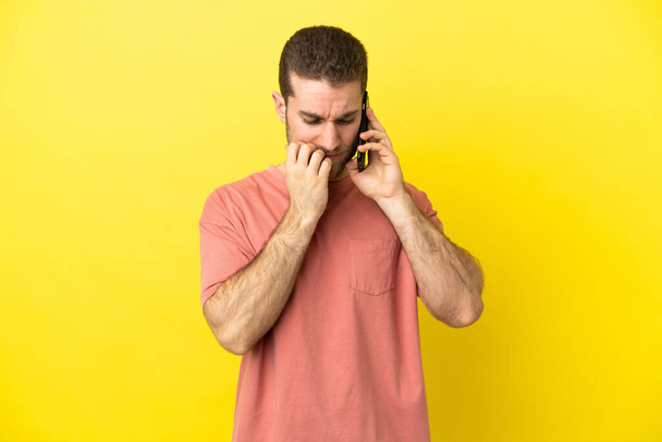 Handsome blonde man using mobile phone over isolated background having doubts - Photo, image