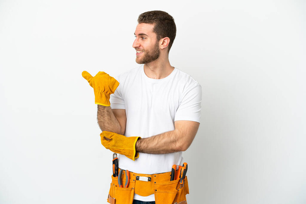 Young electrician man over isolated white wall pointing to the side to present a product - Photo, Image