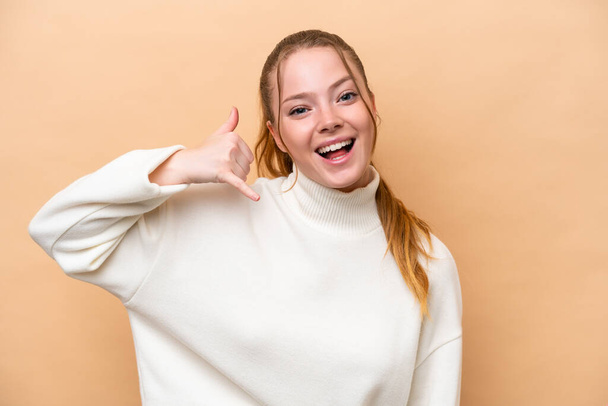 Young caucasian woman isolated on beige background making phone gesture. Call me back sign - Fotó, kép
