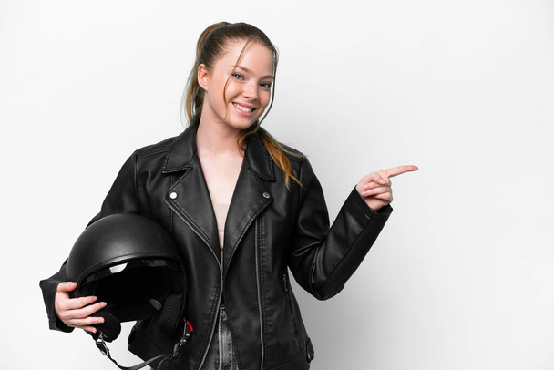 Young caucasian girl with a motorcycle helmet isolated on white background pointing finger to the side - Фото, изображение