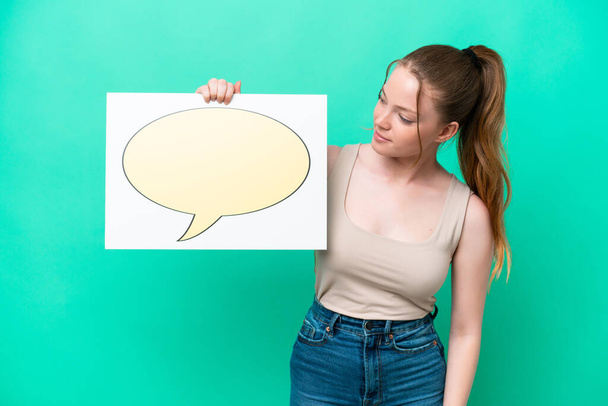 Young caucasian woman isolated on green background holding a placard with speech bubble icon - Foto, Bild