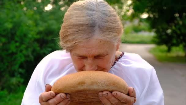 Grandmother with Ukrainian bread in her hands. Selective focus. Food. - Záběry, video