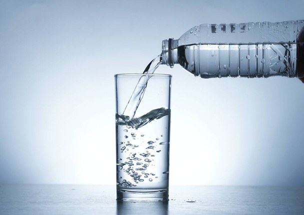 水ボトルからガラスに水を注ぐイメージ - 写真・画像
