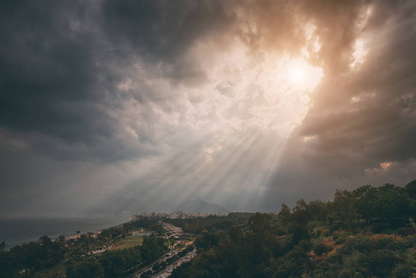 Majestic and dramatic sunlight beams through dense clouds at Konyaalti beach in Antalya, Turkey. Travel destinations backgrounds - Фото, зображення