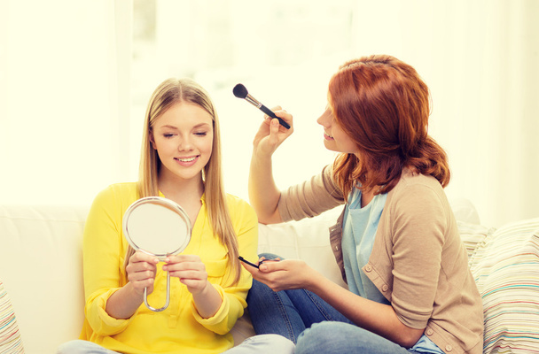 two smiling teenage girls applying make up at home - Foto, Imagen