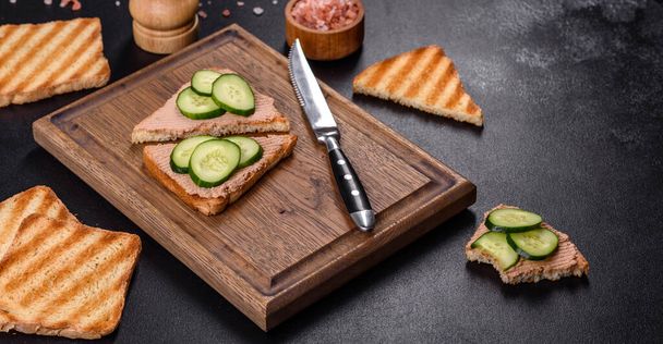 Вкусный свежий сэндвич с куриной печенью с хрустящим тостом, маслом и огурцом. Быстрая здоровая закуска - Фото, изображение