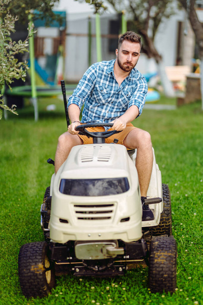 Gardening details with worker using lawn tractor - Photo, Image