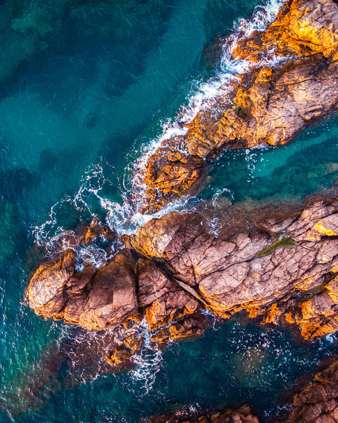 Uitzicht vanuit de lucht op het zeegezicht van de rotsen en de turquoise blauwe zee. Conceptuele achtergrond van zomervakanties op het strand. - Foto, afbeelding