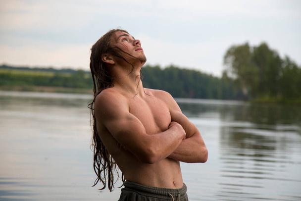 Portrait of a village teenage boy in the river. A long-haired teenager lives harmoniously in nature.  - Foto, immagini