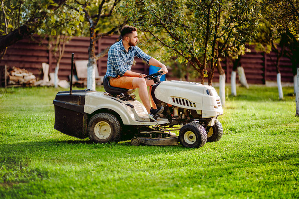 Industry details - portrait of gardener smiling and mowing lawn, cutting grass in garden - 写真・画像
