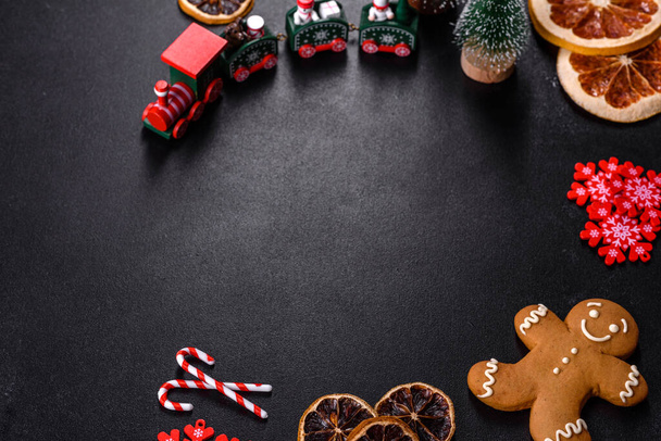 Вкусное свежее шоколадное печенье на темном бетонном фоне с рождественскими игрушками, сушеными цитрусовыми и игрушечными елками. Подготовка праздничного стола - Фото, изображение
