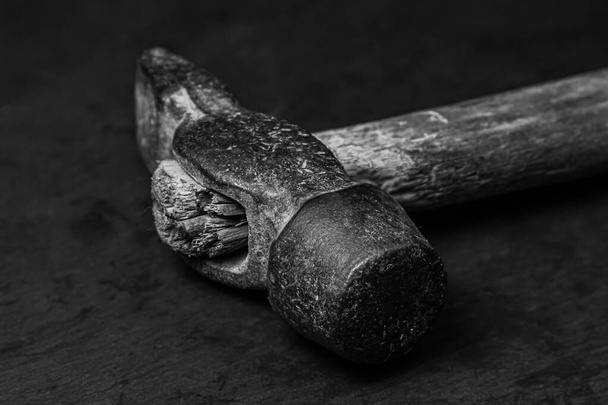 Old hammer on a black background. Black and white photograph of a working tool. old working tool - Photo, Image