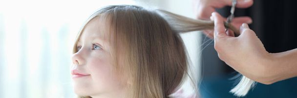 Hairdresser cutting hair of little girl in beauty salon. Hairdressing services for children concept - Foto, Bild