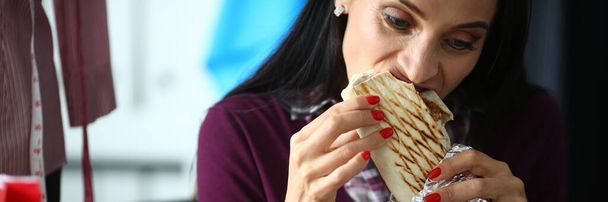 Jovem mulher gananciosamente treme delicioso shawarma. Conceito de receita Shawarma - Foto, Imagem