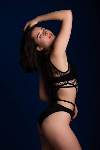 Woman posing in seductive black lingerie. Attractive beauty lady advertising underwear slim body on dark blue background free space for text - Fotó, kép