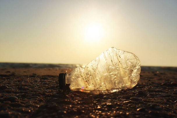 Plastic bottle thrown on the beach . Concept of environmental pollution and damage to nature and animals - Фото, изображение