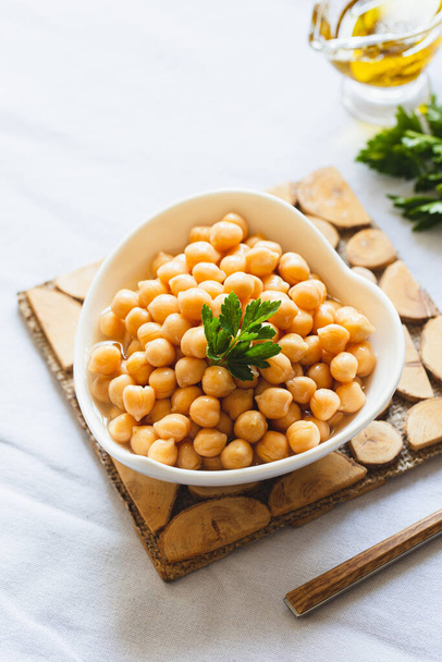 Cooked chickpeas in white bowl. Ingredient for Tasty vegetarian food. Boiled chickpeas, selective focus - Фото, изображение