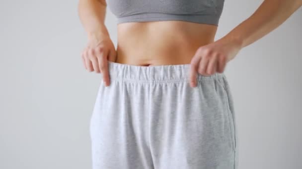 Una donna si mette i pantaloni. Concetto di buona salute, sana digestione e funzione intestinale - Filmati, video