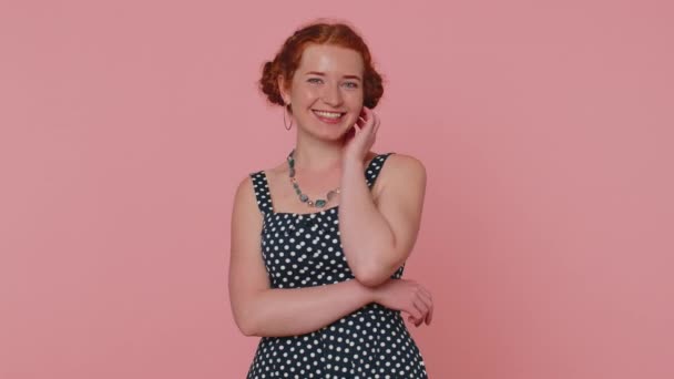 Cheerful lovely redhead young woman in black dress smiling, looking at camera, flirting. Adult fashion red hair model girl indoors studio shot isolated on pink background. Female nature beauty - Filmagem, Vídeo
