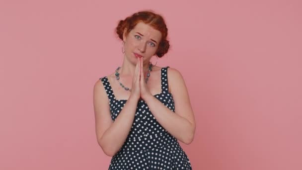 Please, God help. Young redhead woman praying, looking upward and making wish, asking with hopeful imploring expression, begging apology. Ginger girl with freckles isolated on pink studio background - Footage, Video