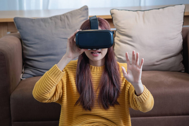 relieve stress on vacation Happy Asian woman relaxing at home playing VR 3D virtual reality game on vacation. - Foto, Imagen