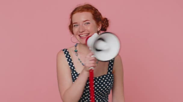 Lachende vrolijke roodharige vrouw in gesprek met megafoon, verkondigen van nieuws, luid aankondigen van verkoop advertentie, waarschuwen met behulp van luidspreker om spraak te schreeuwen. jong gember meisje op roze studio achtergrond - Video