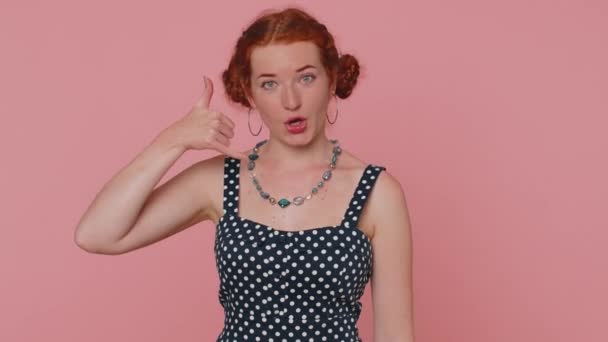 Call us, here is contact number. Redhead young woman seller looking at camera doing phone gesture like says hey you call me back. Adult ginger girl indoors studio shot isolated on pink background - Footage, Video