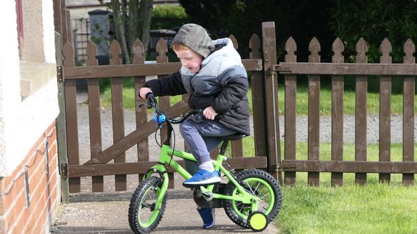 Piros hajú fiú szórakozás játszik a kerékpár a kertben - Fotó, kép