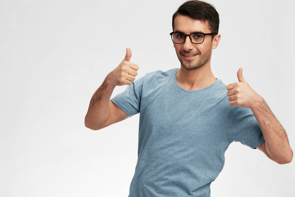 Hombre alegre mano gesto camiseta gafas estilo de vida fondo claro. Foto de alta calidad - Foto, imagen
