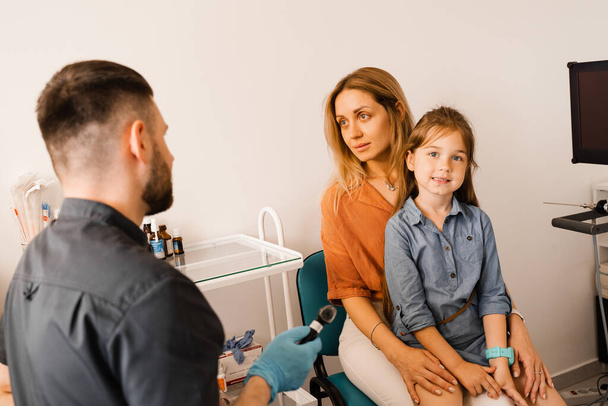 Woman and her child daughter visit ENT doctor. Consultation about endoscopy of nose for family with otolaryngologist in a medical clinic - Фото, изображение
