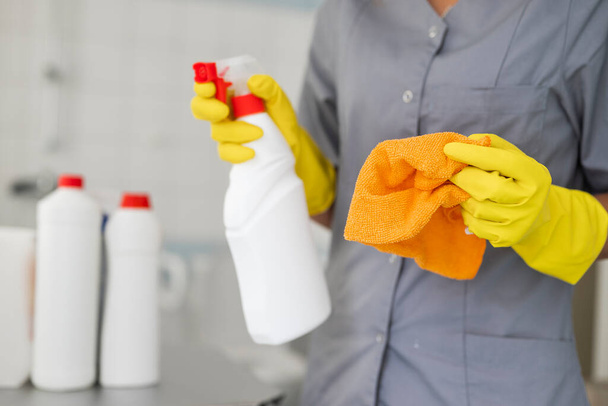 trabalhador do hotel menina com produtos de limpeza fazendo limpeza no banheiro com um pano e um meio de limpeza e desinfecção - Foto, Imagem