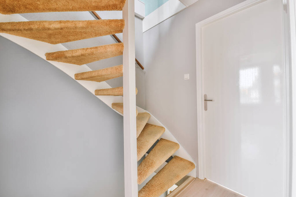 Escalier en colimaçon reliant les niveaux de la maison moderne avec plancher en bois et mursase dans la maison moderne - Photo, image