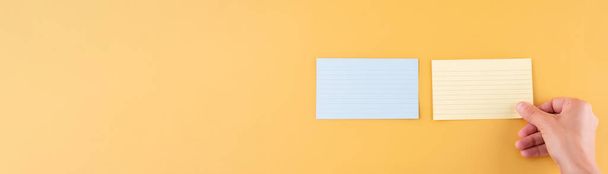 Hand legt leeres Briefpapier und leeres Papier auf einen gelben Hintergrund. Raum für Text. - Foto, Bild