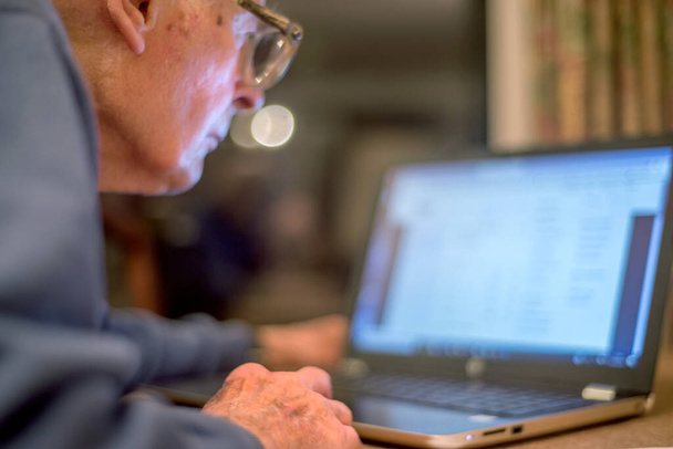 Staruszek od 93 lat ma problemy z korzystaniem z komputera, by sprawdzić finanse w sieci, co jest bardzo trudne dla starszych ludzi.. - Zdjęcie, obraz