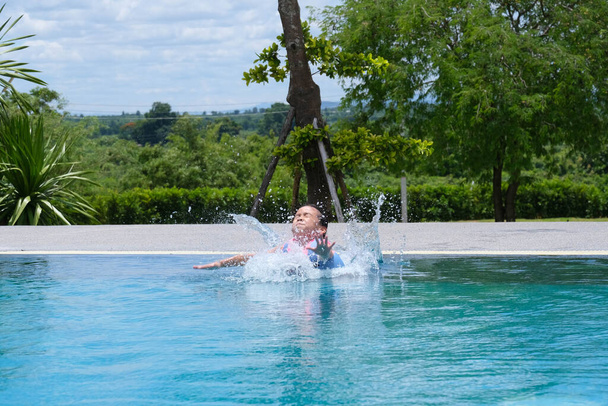Kleines Mädchen in Schwimmweste springt in ein Freibad. Nettes kleines Mädchen spielt an einem sonnigen Tag im Pool. Sommerliches Lifestylekonzept. - Foto, Bild