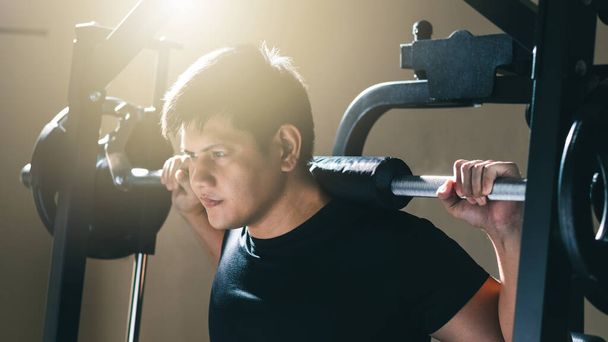 Mann trainiert mit Langhantel, Krafttraining baut Körperkraft auf Im Fitnessstudio in der Morgensonne. - Foto, Bild