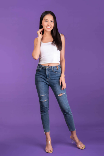 Full body length photo , portrait of Beautiful Asian brunette woman cute girl in white tank top , girl standing smile and happiness isolated on purple background - Valokuva, kuva