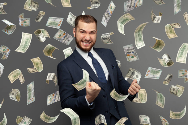 Бизнесмен, стоящий под дождем денег
 - Фото, изображение