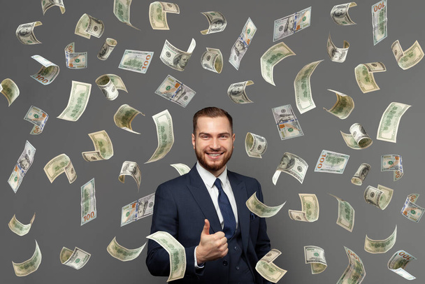 Concepto de negocio, éxito y fortuna. Feliz hombre de negocios sonriente con nosotros dinero del dólar mostrando pulgar hacia arriba - Foto, imagen