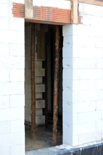 Eine grobe Türöffnung, verstärkte Klinkerstürze, Wände aus Porenbeton und Holzstützen in einem im Bau befindlichen Haus - Foto, Bild