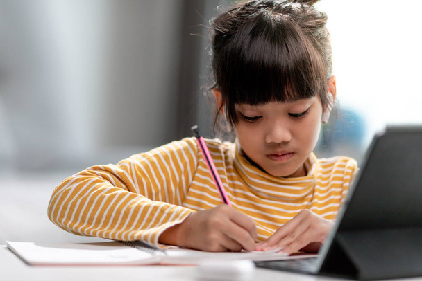 Online öğrenim sınıfındaki Asyalı kız öğrenciler evde Tablet ile çevrimiçi öğrenim görüyorlar. - Fotoğraf, Görsel