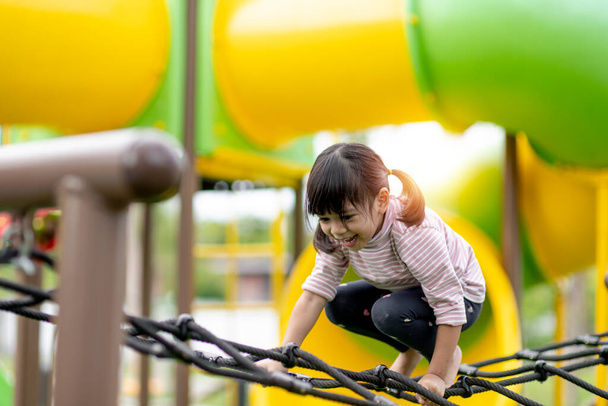 Child playing on outdoor playground. Kids play on school or kindergarten yard. Active kid on colorful slide and swing. Healthy summer activity for children. Little boy climbing outdoors. - Photo, image