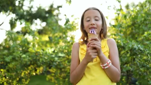 Cute girl with braces eating italian ice cream cone smiling while resting in park on summer day, child enjoying ice cream outdoor, happy holidays, summertime - Video