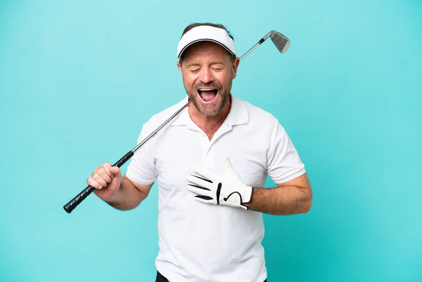 Middle age caucasian golfer player man isolated on blue background smiling a lot - Foto, Imagem