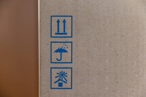 Markings on the cardboard box. Three blue shipping symbols. Top. Protect from rain. Protect from sunlight. Selective focus. - Photo, Image